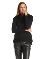 Buzo de punto color beige con cuello volcado amplio, mangas largas acanaladas y torso liso. Presenta una costura central vertical, ruedo con tajos laterales y largo asimétrico, siendo más largo en la parte posterior.