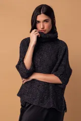 Sweater tipo poncho de tejido de punto grueso en color negro, con cuello alto tipo polera y mangas tres cuartos con puños vueltos.