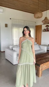 Vestido largo de gasa color verde sage, con escote halter y espalda regulable. Presenta detalles de volados fruncidos en diagonal a lo largo del diseño.