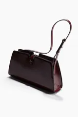 Cartera bandolera color bordó de cuero charolado, con correa fina ajustable y cierre metálico dorado en la parte frontal. Cuenta con un bolsillo interior con cierre y está forrada.