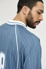 Camiseta de fútbol celeste con rayas verticales, cuello polo y mangas 3/4 con puños blancos. Incluye el número 78 en el frente y logos estampados.