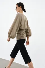 Cuerpo de punto con cuello redondo y mangas largas abullonadas. Presenta un diseño con cintura entallada y bajo ajustado.