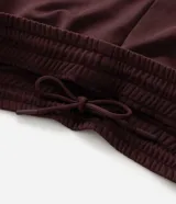 Pantalón deportivo color bordó con rayas blancas laterales, cintura elástica con cordón ajustable, bolsillos laterales y logo pequeño en el muslo.