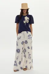 Blusa azul marino de algodón, con mangas abullonadas cortas de tela plana y gran bordado de rosa en tono crudo en el pecho.