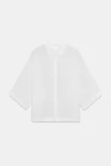 Camisa amplia de corte oversize confeccionada en una mezcla de lyocell y ramio. Presenta cuello solapa, mangas por debajo del codo y cierre frontal con botones ocultos por solapa. Incluye un detalle de pliegue en la espalda.