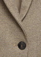 Chaqueta entallada de corte clásico con estampado de micro pata de gallo en tonos tierra. Presenta cuello con solapa, cierre frontal de un botón, bolsillos laterales con solapa y manga larga.