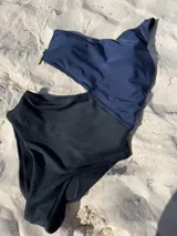 Trikini negro y azul marino, con diseño asimétrico de un solo hombro y abertura lateral.