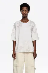 Remera de corte oversize con escote redondo y mangas cortas, confeccionada en algodón con un sutil estampado de textura animal print en tonos neutros.