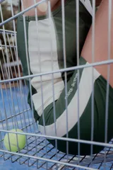 Calza corta deportiva verde con franjas laterales color crema y logo estampado en la pierna.