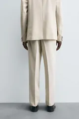 Pantalón de corte recto confeccionado en tejido con lana, color beige. Presenta bolsillos frontales, bolsillos traseros de vivo y cierre frontal con cremallera y botón.