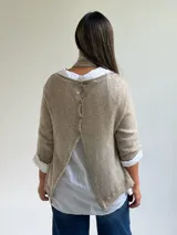 Sweater de punto fino en color beige, con cuello redondo y mangas tres cuartos. El diseño incluye una bufanda integrada del mismo tejido con detalles de puntilla en los extremos.