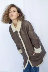 Campera tipo gamulán de cuero genuino en color marrón, con interior y detalles en corderito sintético color crema. Presenta cierre frontal con botones, cuello solapa y puños con vuelta.