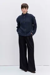 Cardigan de punto acanalado en color azul marino, con cuello alto y cierre frontal de botones. Presenta un diseño de hombros caídos y corte holgado.