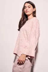 Sweater de punto con efecto jaspeado, de corte oversize, cuello redondo y mangas largas con terminación acampanada tipo volado.