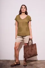 Remera de algodón color blanco con cuello en V y mangas cortas. Presenta un diseño con flores bordadas en relieve y detalles calados en el tejido.