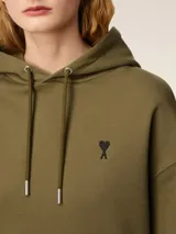 Buzo blanco con capucha y bolsillo tipo canguro, con logo bordado en el pecho.