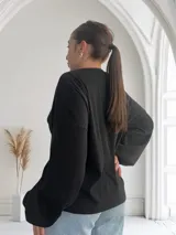 Blusa negra de tejido acanalado con cuello redondo y mangas largas.
