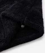 Buzo de tejido peludo color negro, con cuello alto y cierre frontal parcial. Presenta mangas largas con puños elásticos, bolsillo tipo canguro y etiqueta decorativa en el pecho.