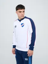 Buzo deportivo Umbro del Club Nacional de Football, modelo Nexo, para hombre. Diseño en color blanco con mangas azules y detalles en rojo, con cuello redondo y el escudo del club bordado en el pecho.