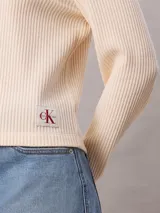 Remera de manga larga Calvin Klein confeccionada en tejido waffle de color beige, con cuello redondo y puños en contraste de color negro. Presenta un pequeño parche con el logo de la marca en el lateral inferior.