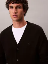 Cárdigan de manga larga confeccionado en lana merino, con cuello en V y cierre frontal de botones. Presenta un diseño de corte regular con el logo de la marca bordado discretamente en el pecho.