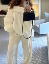 Buzo tejido de punto color crudo con diseño off-shoulder, textura acanalada y calce relajado.