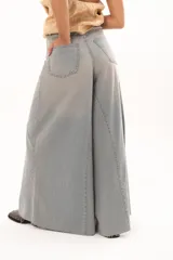 Pantalón de jean tiro alto con diseño de pierna extra ancha y caída fluida. Presenta costuras verticales que realzan su estructura, bolsillos funcionales y terminación de ruedo deshilachado.