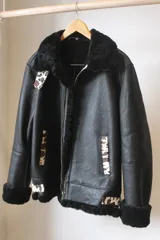 Campera tipo bomber de cuero genuino color negro, con interior y cuello de piel sintética negra. Presenta detalles decorativos en estampado animal print tipo vaca en los bolsillos, puños y cuello.