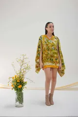 Chaleco de lana merino color crema, con escote en V y diseño sin mangas. Se usa sobre una camisa mostaza de mangas largas con puños elásticos.