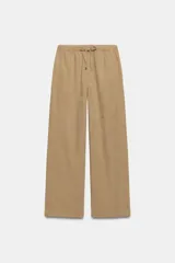 Pantalón de tiro medio color beige con cintura elástica ajustable mediante cordones, bolsillos frontales y diseño de pierna ancha.