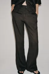 Pantalón flare de tiro medio confeccionado en lino color marrón. Cuenta con cintura con trabillas, bolsillos delanteros, perneras de corte evasé y cierre frontal con cremallera y botón.