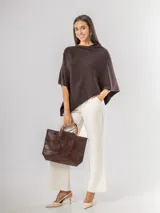 Poncho de corte holgado y diseño minimalista, confeccionado en tejido liviano de color beige, con cuello redondo y caída fluida.