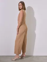 Mono color beige de crepe, marca Sharagano. Escote en V cruzado, sin mangas, con cintura elastizada y lazo de ajuste. Abertura central en espalda con cierre invisible y doble abotonadura. Bolsillos inclinados en delantera con aplique de botones.