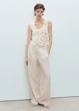 Top de crochet color crudo, sin mangas, con cuello redondo y diseño floral translúcido.