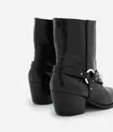 Bota corta de cuero sintético color negro, estilo western, con puntera fina, taco cuadrado y detalles de tachas plateadas.