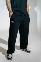 Pantalón de jogging negro de corte holgado, con cintura elástica ajustable mediante cordón y logo pequeño estampado en la pierna derecha.