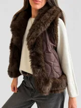 Chaleco acolchado color marrón con diseño matelassé y amplias solapas de piel sintética en tono chocolate. Presenta un corte recto y sin mangas, ideal para superposiciones.