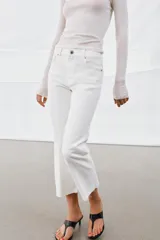 Jeans de tiro medio con corte flare y largo cropped. Presentan diseño de cinco bolsillos, cierre frontal con cremallera y botón, raya planchada en el delantero y bajo desflecado con acabado evasé.