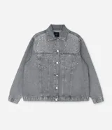 Campera de jean gris con efecto desteñido, corte oversized, cuello inglés, cierre frontal con botones niquelados y aplicaciones de brillos y piedras en la parte superior delantera.