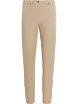 Pantalón chino color beige de sarga elástica, corte slim, con cierre de cremallera y botón, bolsillos traseros de ojal y logo de Tommy Hilfiger bordado en la parte trasera.