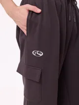 Babucha de estilo cargo en color negro, confeccionada en tejido de algodón y poliéster. Presenta cintura elástica con cordón ajustable, bolsillos laterales tipo cargo y puños elásticos en los tobillos.