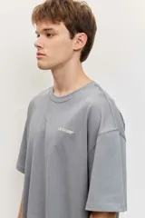 Remera blanca de manga corta, corte oversize, con estampa en la espalda de una flor sobre fondo difuminado verde y blanco.