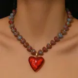 Collar corto con cuentas de corazones rojas y grises separadas por pequeñas cuentas doradas. Dije colgante de corazón rojo brillante.