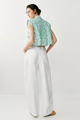 Jeans blancos de tiro medio y pernera ancha con corte barrel que se estrecha hacia el tobillo. Presenta cinco bolsillos, pliegues delanteros y cierre frontal con cremallera y botón metálico.