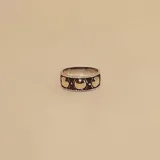 Anillo de banda ancha fabricado en plata con detalles circulares en oro aplicados sobre una base con acabado oxidado.