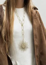 Collar largo de bronce compuesto por una cadena de eslabones ovalados y un gran dije colgante con diseño de sol.