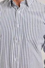 Camisa de manga larga confeccionada en tejido de algodón Oxford, con diseño de rayas verticales en tonos gris y blanco, cuello abotonado y bolsillo frontal.