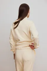 Campera deportiva de felpa de algodón color beige, de corte ajustado, con cuello elevado, cierre frontal y bolsillos laterales discretos. Presenta puños y bajo acanalados.