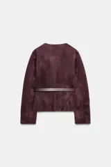 Blazer de cuello redondo y manga larga, confeccionado en tejido efecto ante. Presenta cierre frontal con botones, bolsillos con tapeta en el pecho y cinturón ajustable en la cintura.