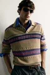 Sweater de punto jacquard de algodón y lino, color tostado con diseño de franjas geométricas en tonos violeta, fucsia y verde. Presenta cuello polo con cierre frontal de tres botones, mangas largas y puños y cintura en rib.